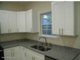 kitchen featuring white cabinets, dark stone countertops, and sink