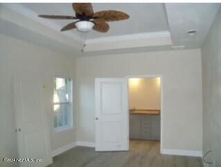 unfurnished bedroom with a closet, a walk in closet, a tray ceiling, and dark hardwood / wood-style flooring