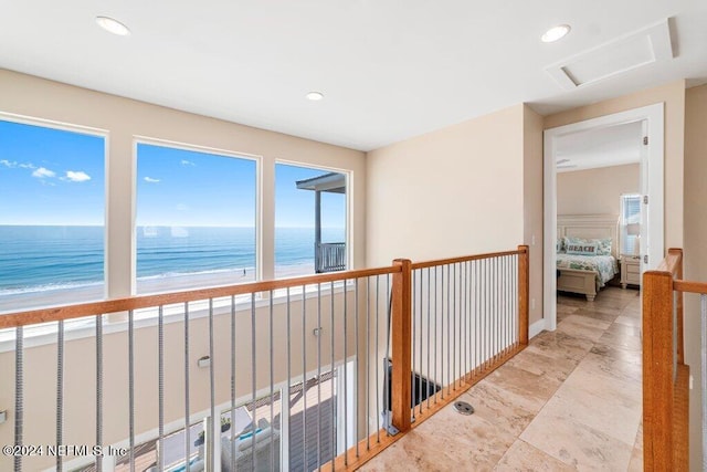 hall featuring light tile flooring, a water view, and a view of the beach