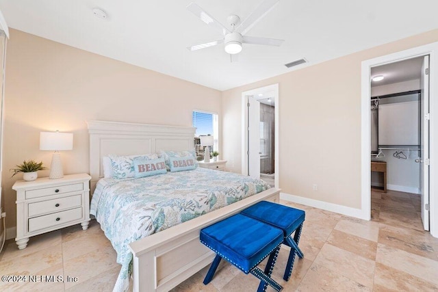 bedroom with light tile floors, ensuite bath, ceiling fan, and a walk in closet