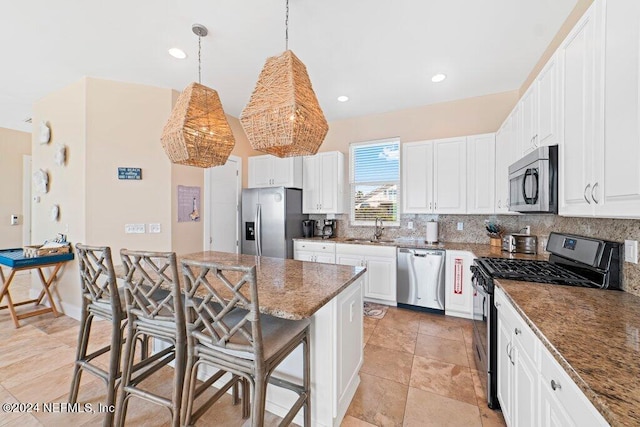 kitchen with tasteful backsplash, a kitchen bar, dark stone countertops, stainless steel appliances, and hanging light fixtures