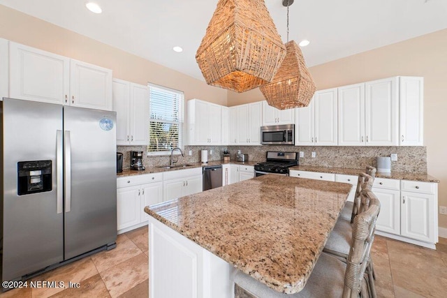 kitchen with appliances with stainless steel finishes, white cabinets, a kitchen island, a breakfast bar area, and backsplash