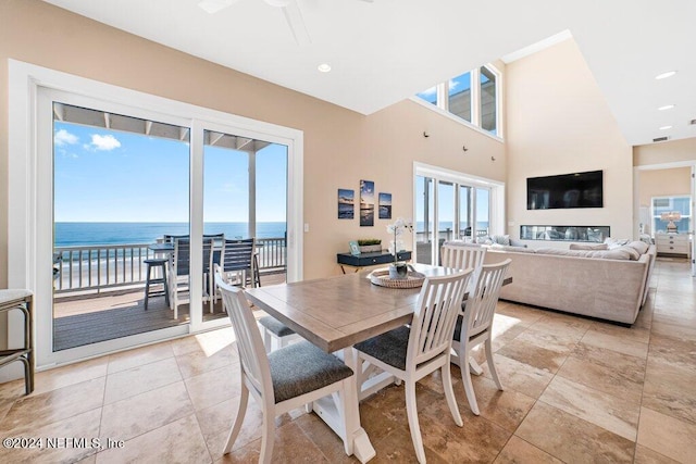 dining room featuring ceiling fan, a water view, and light tile flooring