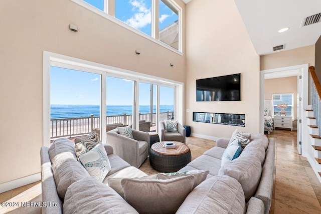 living room featuring a towering ceiling and a water view