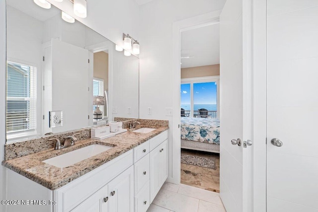 bathroom with tile flooring, vanity with extensive cabinet space, dual sinks, and a water view