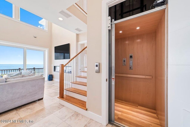 interior space with a barn door, a healthy amount of sunlight, elevator, light hardwood / wood-style flooring, and a water view