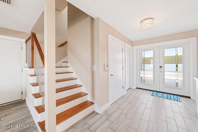 foyer entrance with french doors and light hardwood / wood-style floors