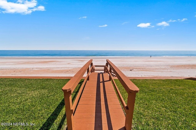 surrounding community featuring a beach view, a water view, and a lawn