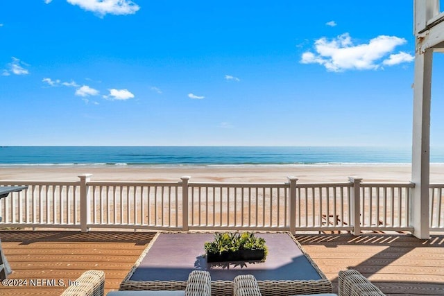 wooden deck featuring a beach view and a water view