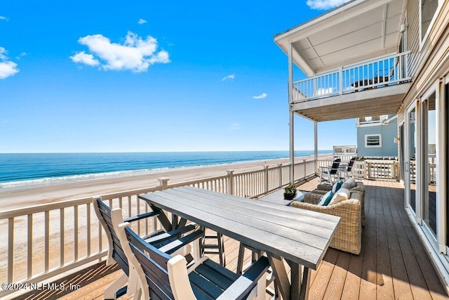 wooden deck featuring a water view and a view of the beach