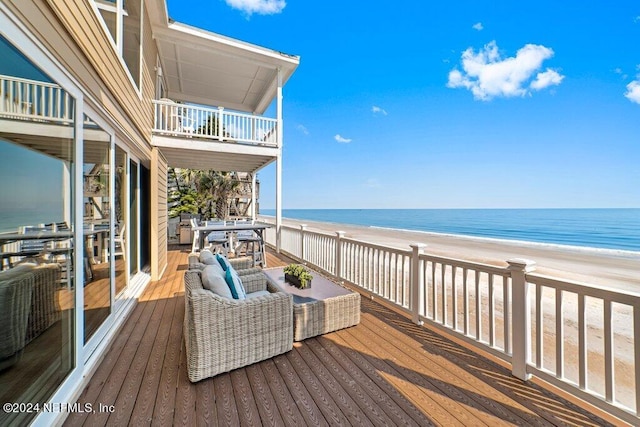 wooden deck with a water view and a beach view