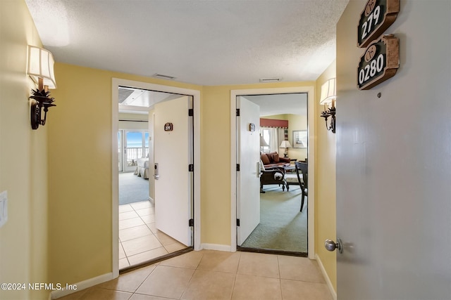 hall featuring light carpet and a textured ceiling