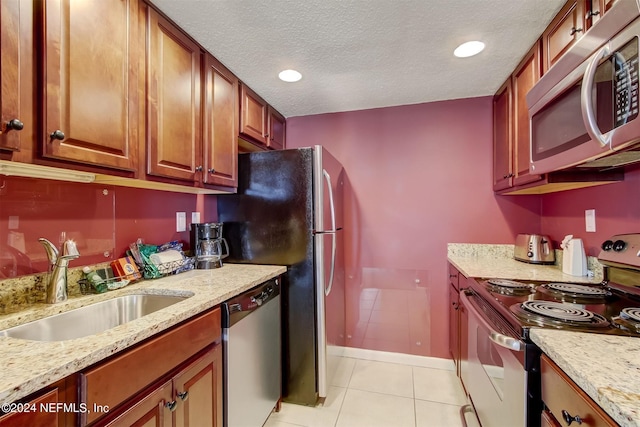 kitchen featuring light stone countertops, appliances with stainless steel finishes, sink, light tile floors, and a textured ceiling