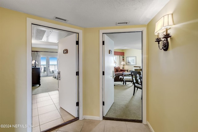 hall featuring light tile floors and a textured ceiling