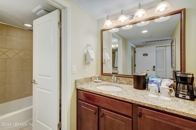 bathroom featuring tiled shower / bath combo, vanity, and a textured ceiling