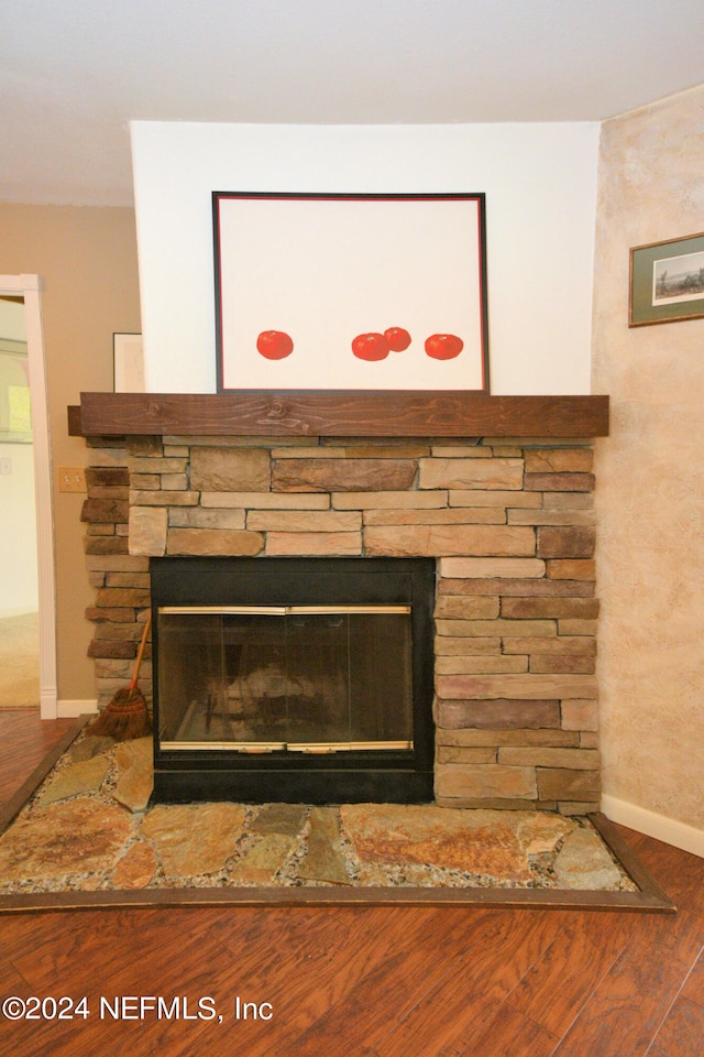 interior details featuring wood-type flooring and a stone fireplace