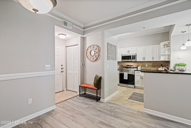 kitchen featuring appliances with stainless steel finishes, backsplash, light tile floors, decorative light fixtures, and white cabinets