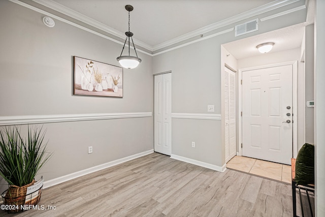 foyer entrance with ornamental molding and light hardwood / wood-style floors