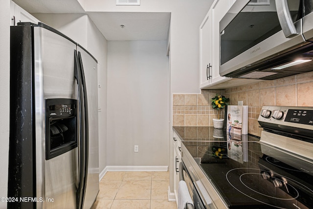 kitchen featuring white cabinetry, backsplash, light tile flooring, and stainless steel appliances