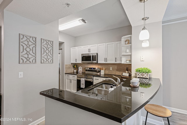 kitchen featuring decorative light fixtures, appliances with stainless steel finishes, tasteful backsplash, white cabinets, and kitchen peninsula