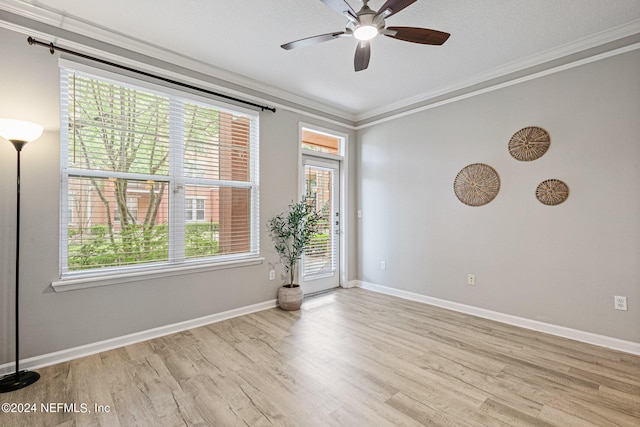 spare room featuring a healthy amount of sunlight, light hardwood / wood-style flooring, and crown molding