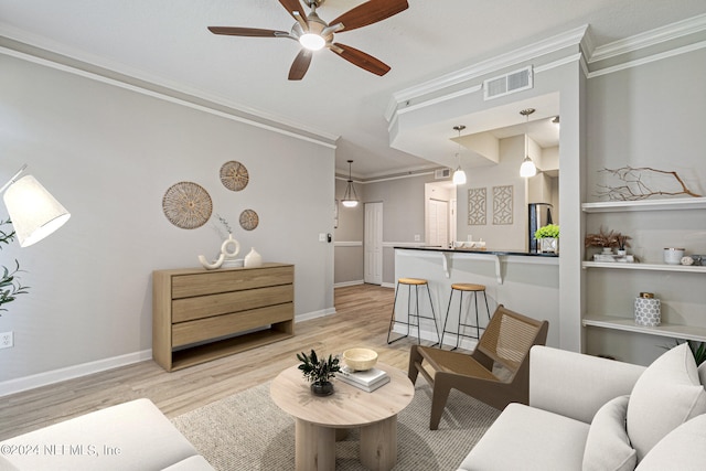 living room with ornamental molding, ceiling fan, and light hardwood / wood-style flooring