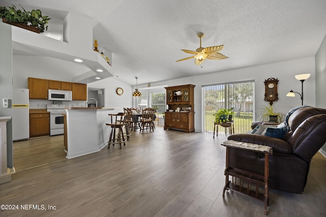 living room featuring a textured ceiling, hardwood / wood-style floors, ceiling fan, and high vaulted ceiling