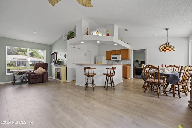 dining space featuring a textured ceiling, ceiling fan, high vaulted ceiling, and light wood-type flooring