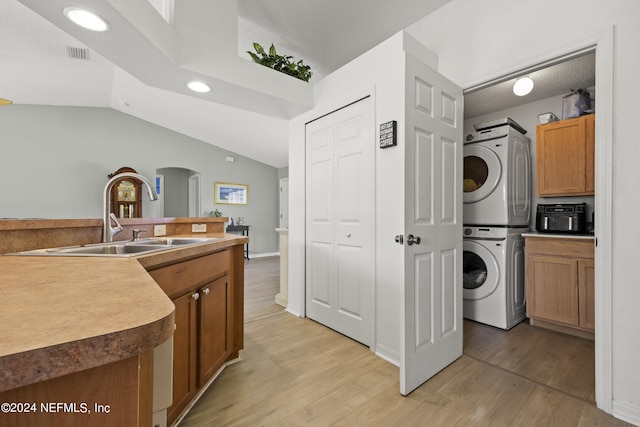 laundry area featuring stacked washer and clothes dryer, light hardwood / wood-style floors, and sink