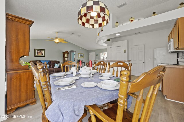 dining area with light hardwood / wood-style flooring, a textured ceiling, ceiling fan, and lofted ceiling