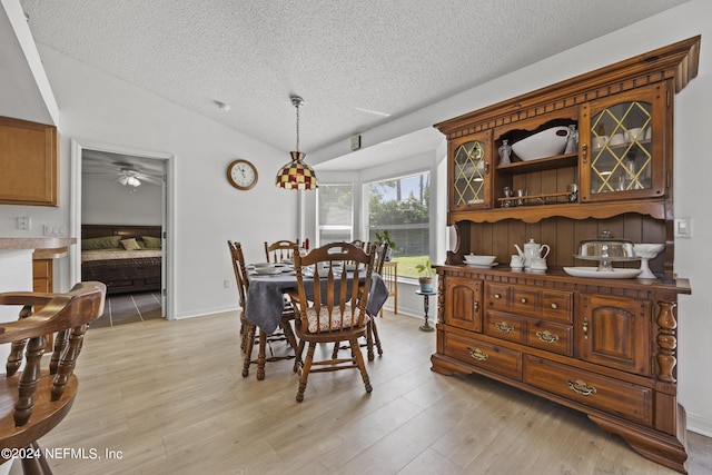 dining room featuring lofted ceiling, light hardwood / wood-style floors, ceiling fan, and a textured ceiling