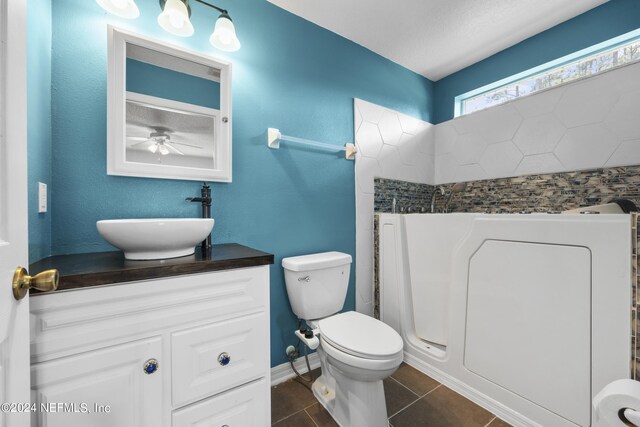 bathroom with walk in shower, ceiling fan, tile floors, vanity with extensive cabinet space, and toilet