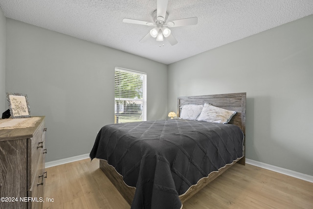 bedroom with a textured ceiling, ceiling fan, and light hardwood / wood-style flooring