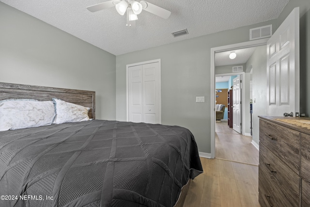 bedroom featuring ceiling fan, a closet, light hardwood / wood-style flooring, and a textured ceiling