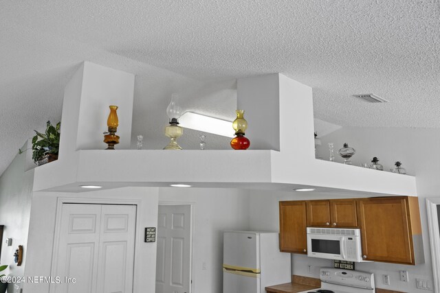 interior space with white appliances and a textured ceiling