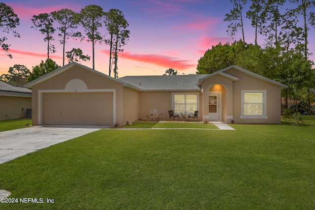 ranch-style home featuring a garage and a yard