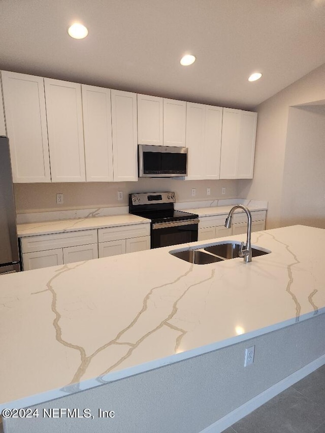 kitchen with white cabinets, stainless steel appliances, a sink, and recessed lighting