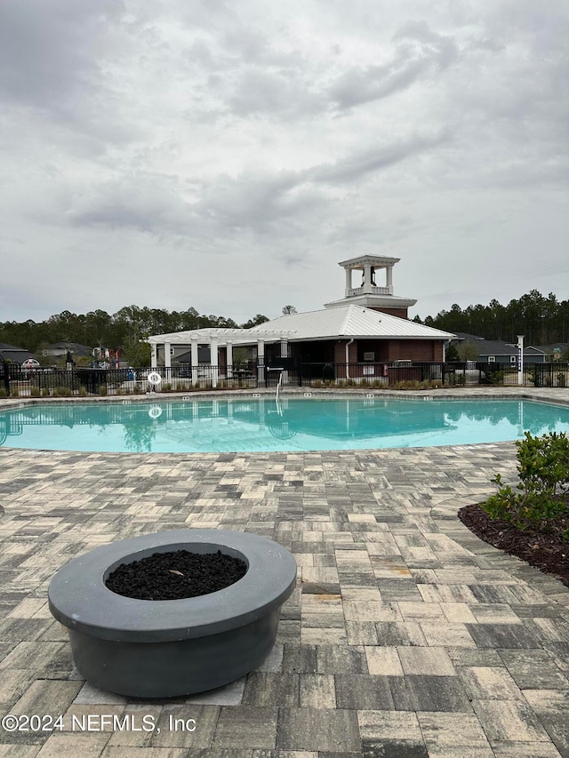 pool with a fire pit, a patio, and fence