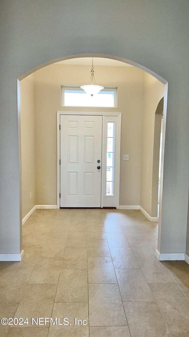 foyer with baseboards and arched walkways