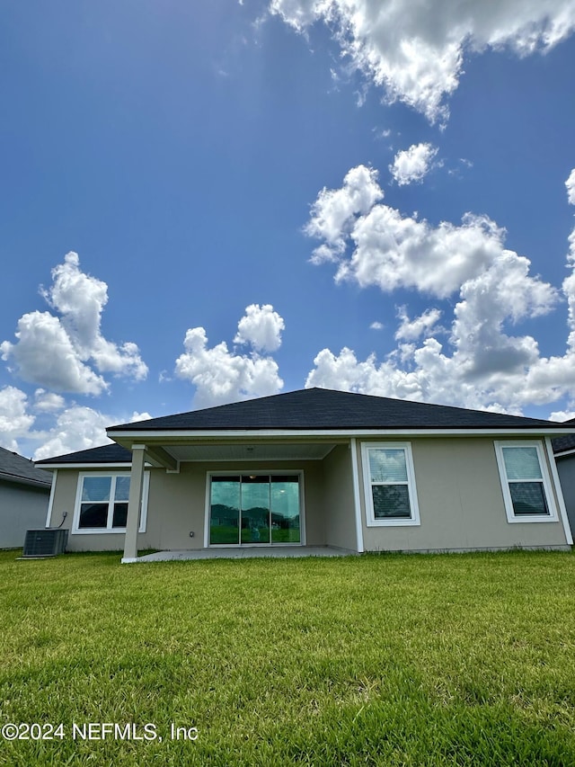 back of house featuring a yard, central air condition unit, and stucco siding