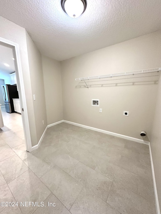 washroom with a textured ceiling, hookup for an electric dryer, laundry area, washer hookup, and baseboards