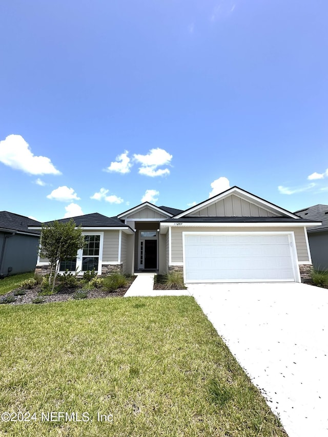 ranch-style house with driveway, a garage, stone siding, board and batten siding, and a front yard