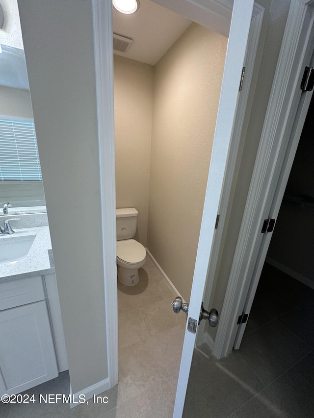 bathroom with visible vents, toilet, vanity, tile patterned flooring, and baseboards