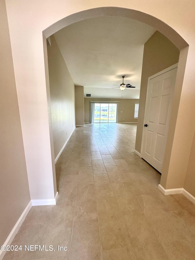 hall featuring visible vents, baseboards, and arched walkways