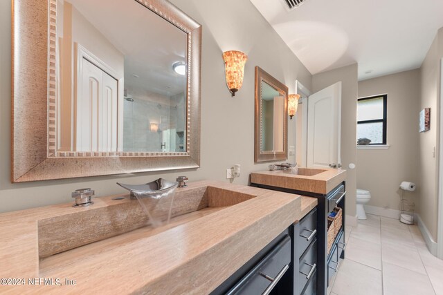 bathroom with tile flooring, toilet, and large vanity