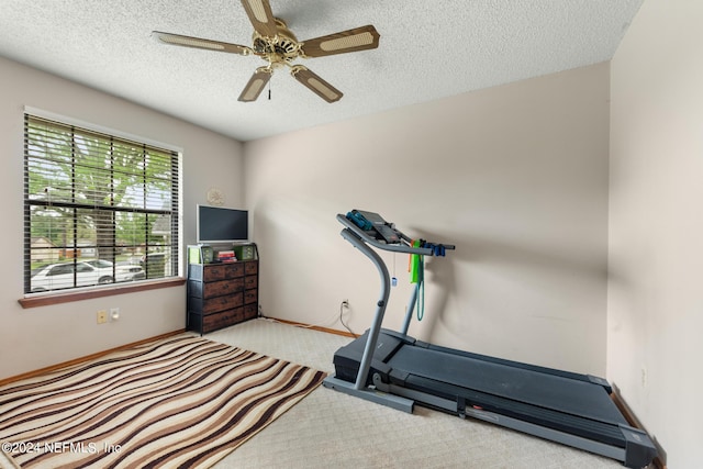 exercise area featuring light carpet, ceiling fan, and a textured ceiling