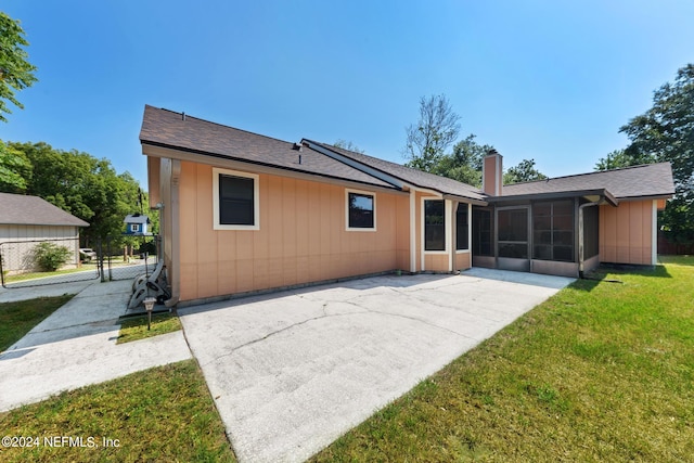 rear view of house with a patio, a sunroom, and a lawn