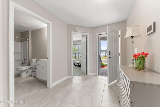 hall with a textured ceiling and light tile flooring