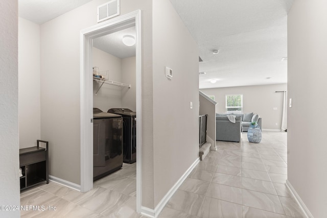 hall featuring independent washer and dryer and light tile floors