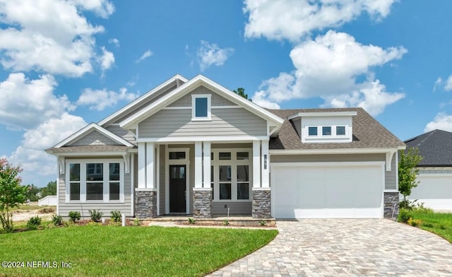 craftsman house featuring a garage and a front lawn